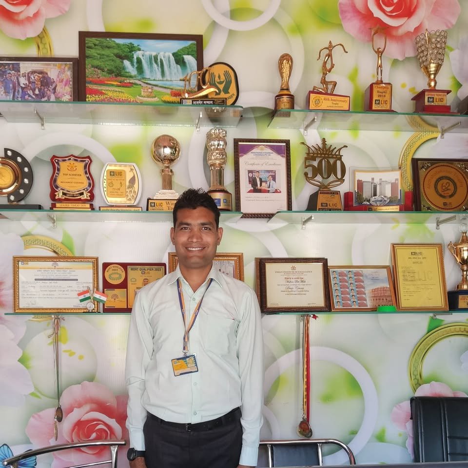 Mohan Lal Mali standing beside his wall of trophies, medals and certificates